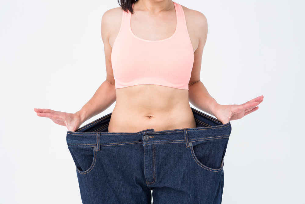 Woman showing her waist after losing weight on white background